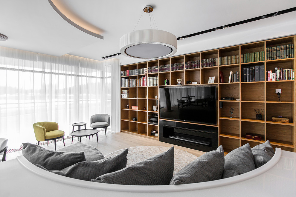 Diseño de biblioteca en casa abierta contemporánea grande con paredes blancas, suelo de madera clara y pared multimedia