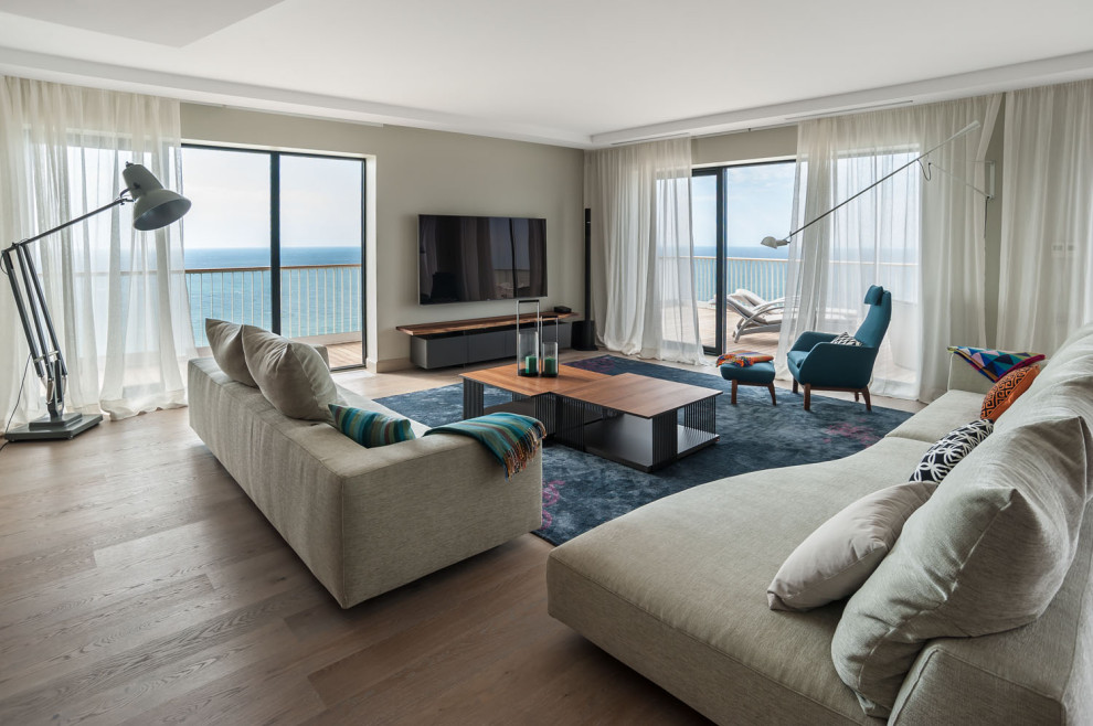 Идея дизайна: гостиная комната в современном стиле с серыми стенами, паркетным полом среднего тона, телевизором на стене и коричневым полом