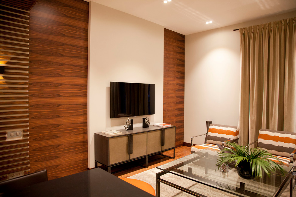 Стильный дизайн: парадная, открытая, объединенная гостиная комната в современном стиле с телевизором на стене - последний тренд