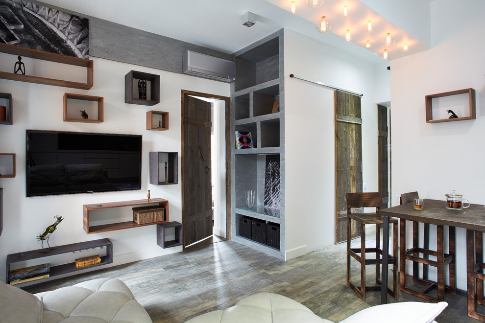 Пример оригинального дизайна: парадная, открытая гостиная комната в стиле лофт с белыми стенами и телевизором на стене