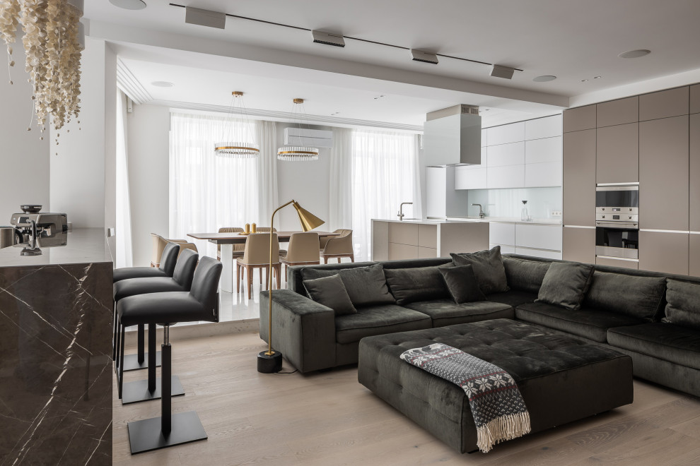 Trendy open concept light wood floor and beige floor living room photo in Other with white walls
