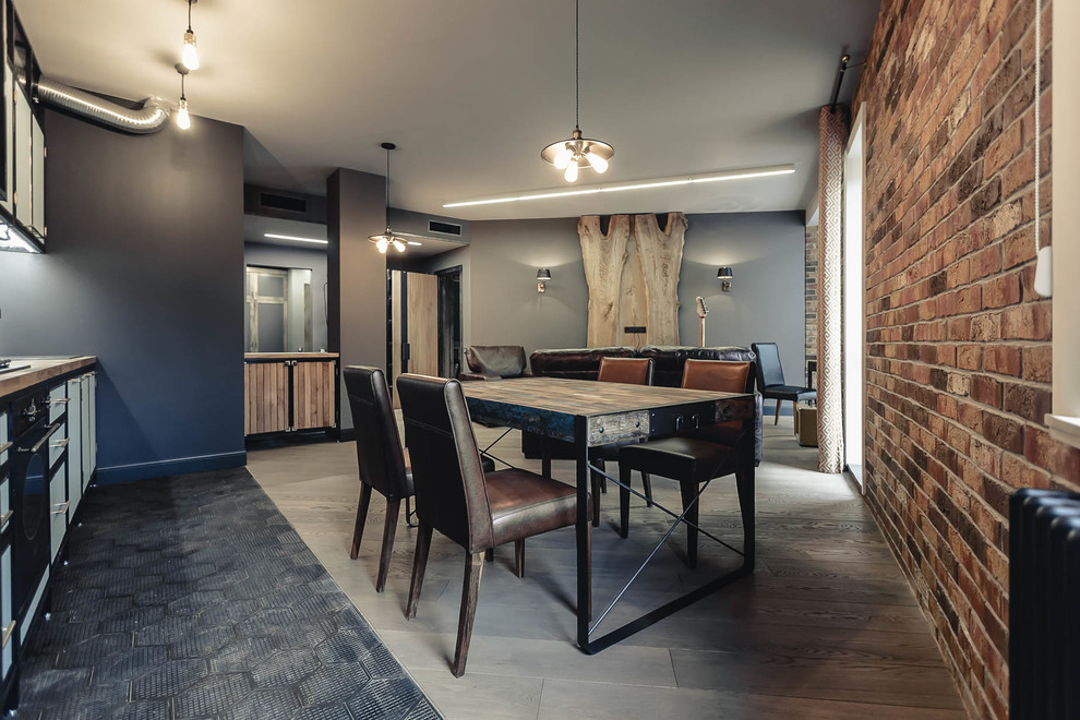 Ejemplo de salón abierto industrial de tamaño medio con paredes marrones, suelo de madera clara, televisor colgado en la pared y suelo beige
