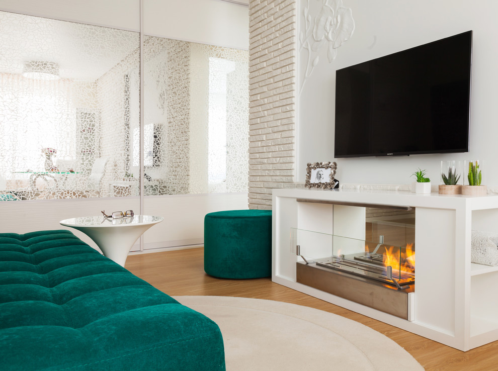 Cette image montre un salon design avec une salle de réception, un mur blanc, une cheminée ribbon et un téléviseur fixé au mur.