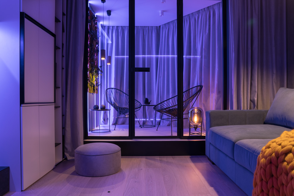Стильный дизайн: маленькая гостиная комната в современном стиле с серыми стенами, светлым паркетным полом, бежевым полом и телевизором на стене для на участке и в саду - последний тренд