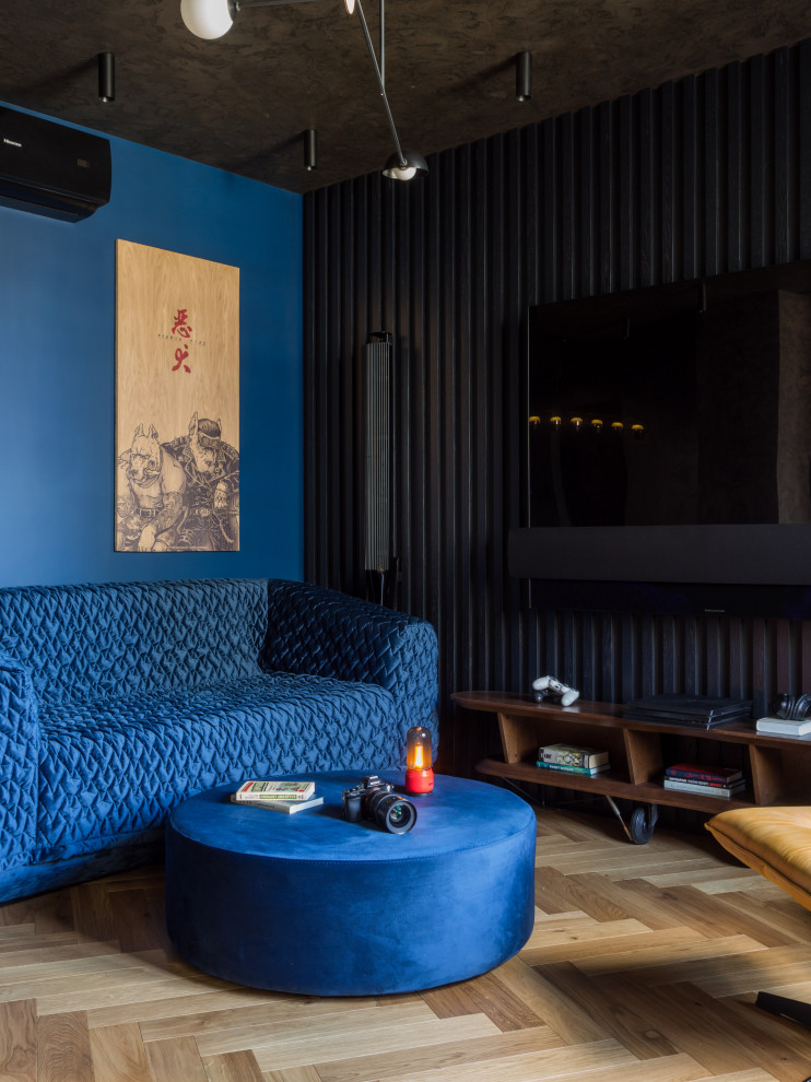 Пример оригинального дизайна: открытая гостиная комната среднего размера в современном стиле с музыкальной комнатой, синими стенами, паркетным полом среднего тона, телевизором на стене и синим диваном без камина