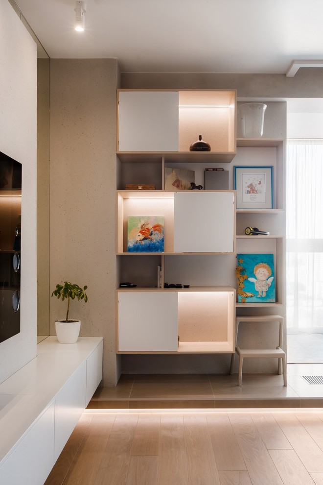 Идея дизайна: открытая гостиная комната среднего размера в современном стиле с с книжными шкафами и полками, серыми стенами, паркетным полом среднего тона, телевизором на стене и бежевым полом