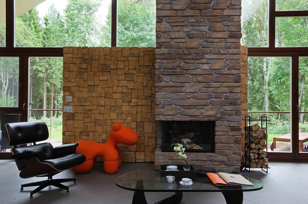 Diseño de salón minimalista de tamaño medio con paredes marrones, suelo de pizarra, chimenea lineal, marco de chimenea de piedra, televisor retractable y suelo gris