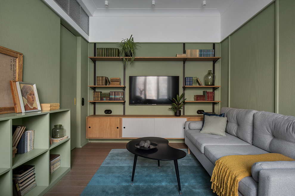 Modelo de salón cerrado minimalista pequeño con paredes verdes, televisor colgado en la pared y suelo marrón