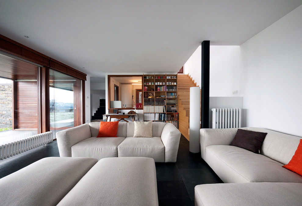 Foto di un grande soggiorno minimal aperto con libreria, pareti bianche e pavimento in ardesia