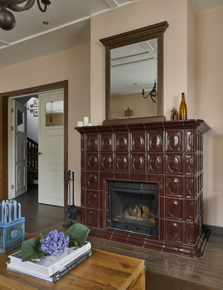 Cette image montre un salon traditionnel avec une salle de réception, un mur beige, un sol en bois brun, une cheminée standard, un manteau de cheminée en carrelage et un sol marron.