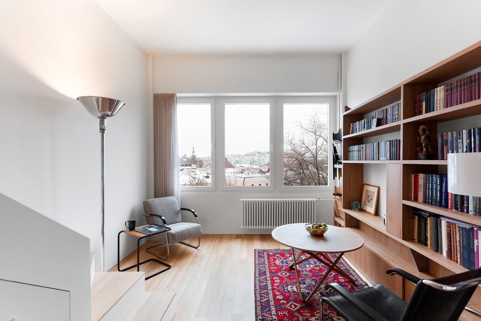 Inspiration för små moderna vardagsrum, med ett bibliotek, vita väggar och mellanmörkt trägolv