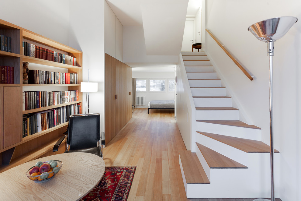 Esempio di un piccolo soggiorno contemporaneo con libreria, pareti bianche e pavimento in legno massello medio