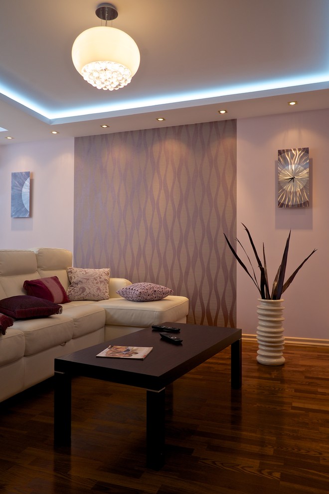 Свежая идея для дизайна: открытая гостиная комната среднего размера в современном стиле с розовыми стенами, темным паркетным полом, подвесным камином, фасадом камина из штукатурки, телевизором на стене и коричневым полом - отличное фото интерьера