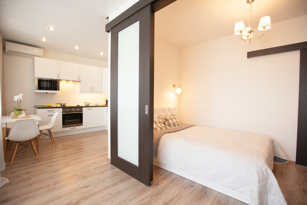 Свежая идея для дизайна: объединенная гостиная комната среднего размера в скандинавском стиле с белыми стенами, полом из ламината, телевизором на стене и коричневым полом - отличное фото интерьера