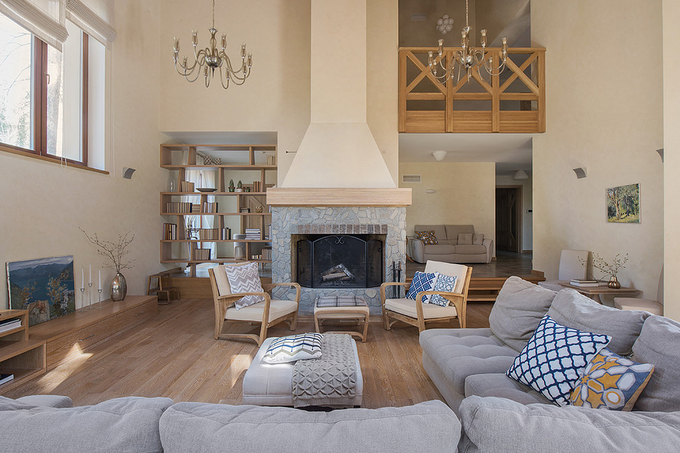 Réalisation d'un salon champêtre ouvert avec un mur beige, un sol en bois brun, une cheminée standard, un manteau de cheminée en pierre, une salle de réception et un sol beige.