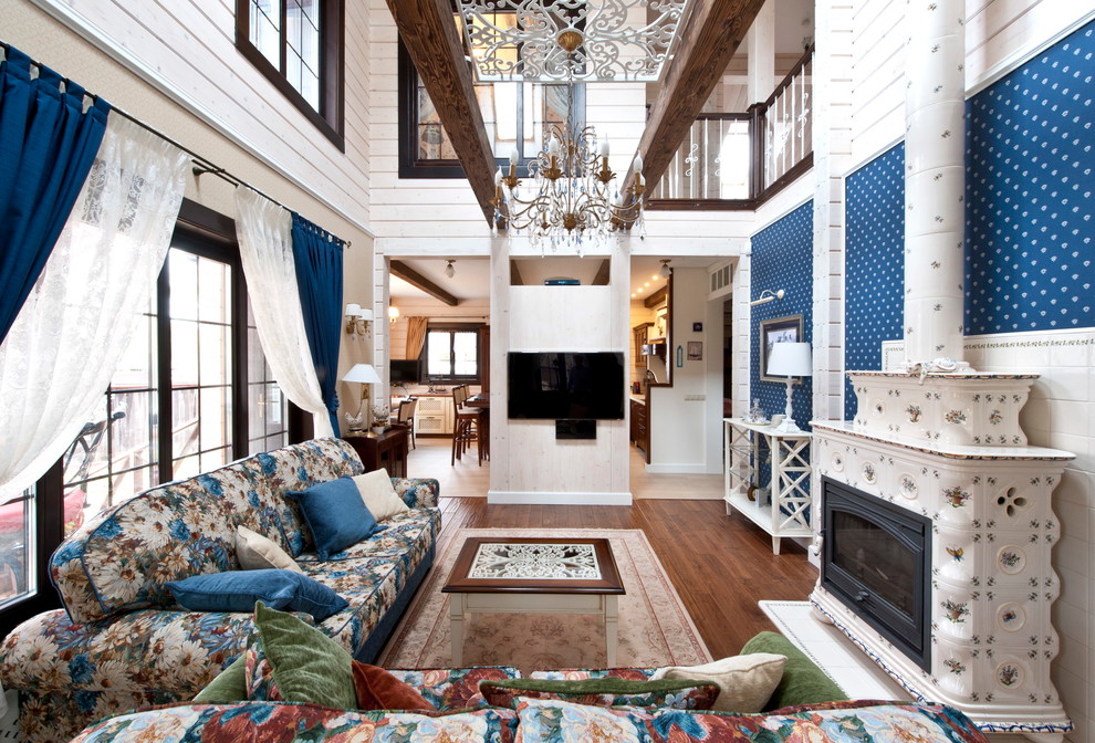 На фото: изолированная гостиная комната среднего размера в стиле кантри с синими стенами, темным паркетным полом, печью-буржуйкой, фасадом камина из плитки, телевизором на стене и коричневым полом с