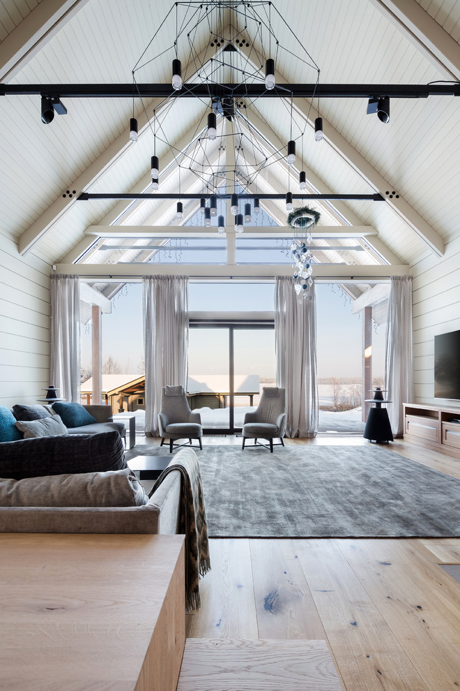 Esempio di un grande soggiorno contemporaneo aperto con parquet chiaro, TV a parete, pareti bianche e pavimento beige