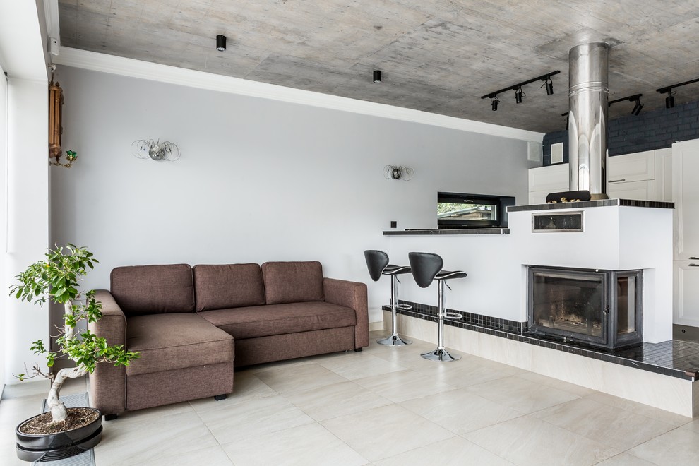Стильный дизайн: объединенная гостиная комната в стиле лофт с стандартным камином и фасадом камина из штукатурки - последний тренд