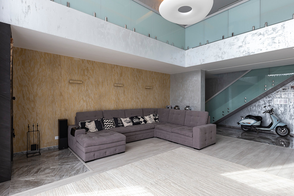Идея дизайна: большая двухуровневая гостиная комната в современном стиле с с книжными шкафами и полками, синими стенами, полом из ламината, угловым камином, фасадом камина из металла, телевизором на стене и серым полом