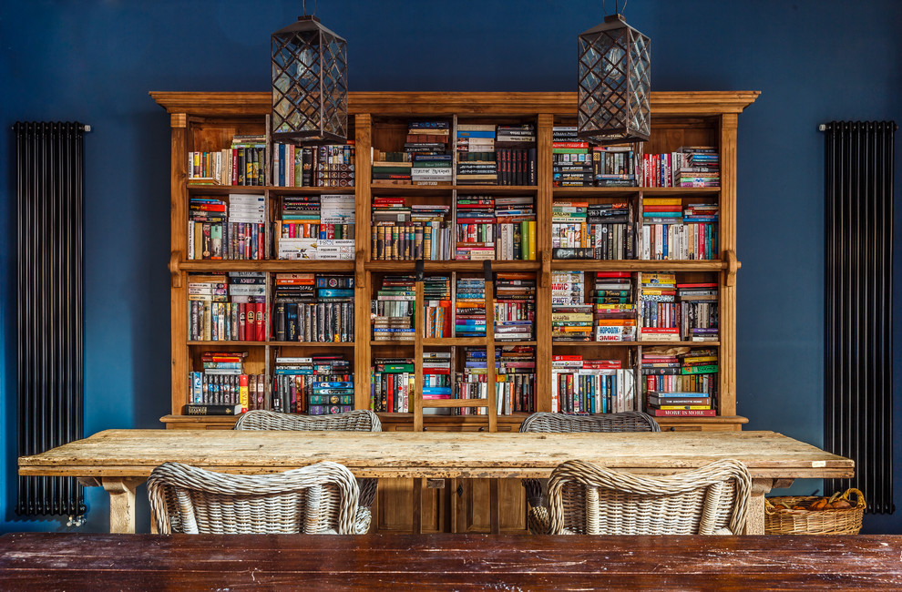 Cette image montre un grand salon bohème ouvert avec une bibliothèque ou un coin lecture et un mur bleu.