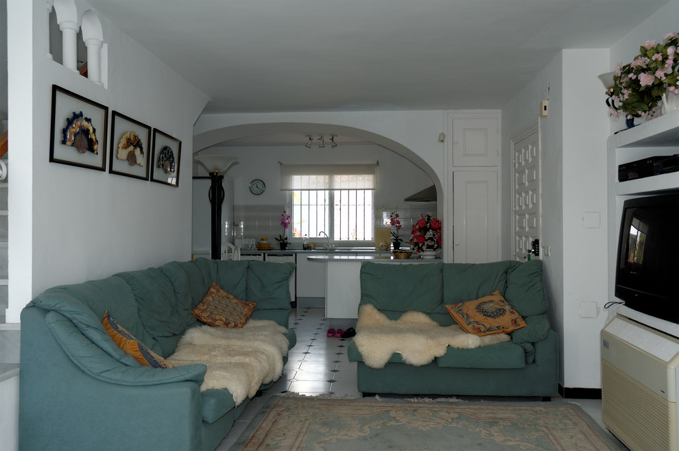 マラガにあるお手頃価格の中くらいな地中海スタイルのおしゃれな独立型リビング (白い壁、セラミックタイルの床、コーナー設置型暖炉、漆喰の暖炉まわり、据え置き型テレビ) の写真