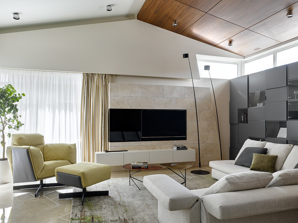 На фото: открытая гостиная комната в современном стиле с белыми стенами, телевизором на стене и бежевым полом с