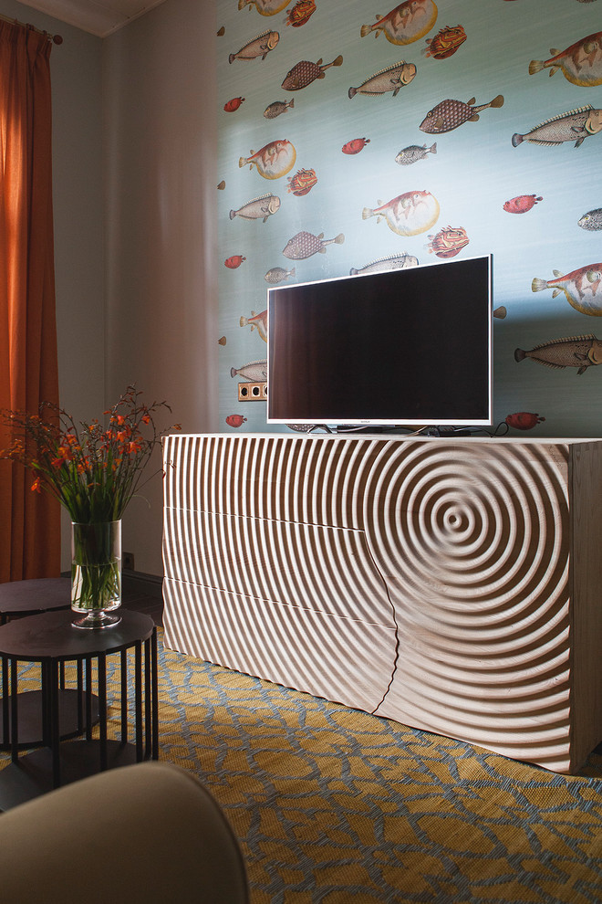 Стильный дизайн: гостиная комната в современном стиле с разноцветными стенами, отдельно стоящим телевизором, ковровым покрытием и обоями за телевизором - последний тренд