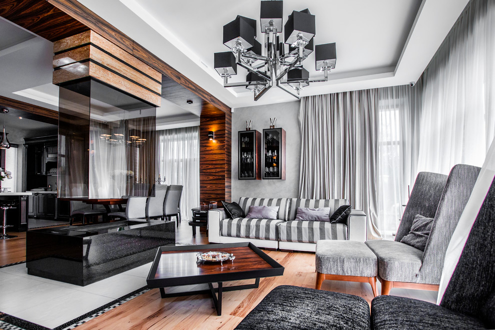 Идея дизайна: парадная, открытая гостиная комната в стиле неоклассика (современная классика) с серыми стенами, паркетным полом среднего тона, двусторонним камином и коричневым полом