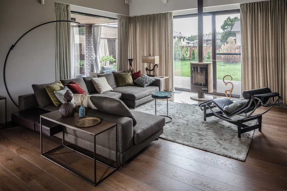 Ispirazione per un soggiorno design aperto con sala formale, pavimento in legno massello medio, stufa a legna e pavimento marrone