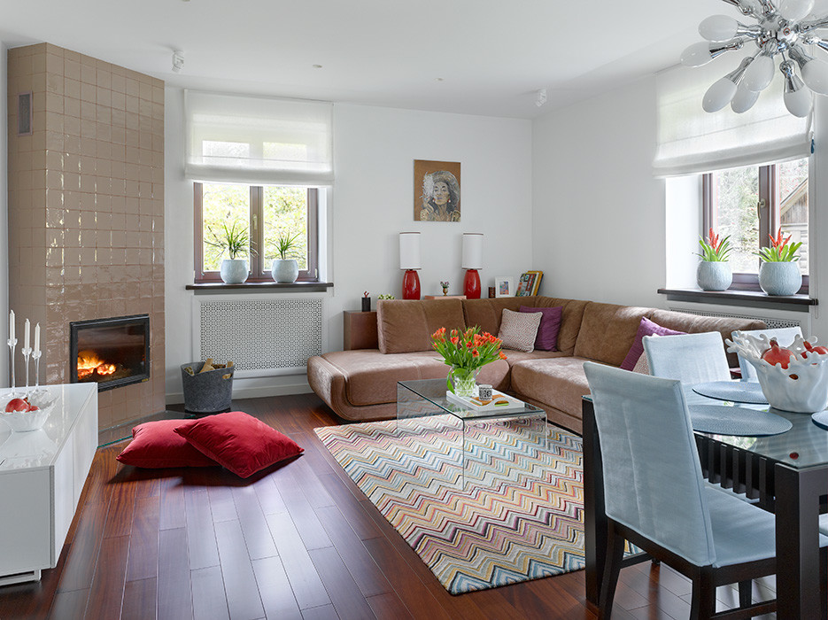 Imagen de salón actual con suelo de madera en tonos medios, chimenea de esquina, marco de chimenea de baldosas y/o azulejos y suelo marrón