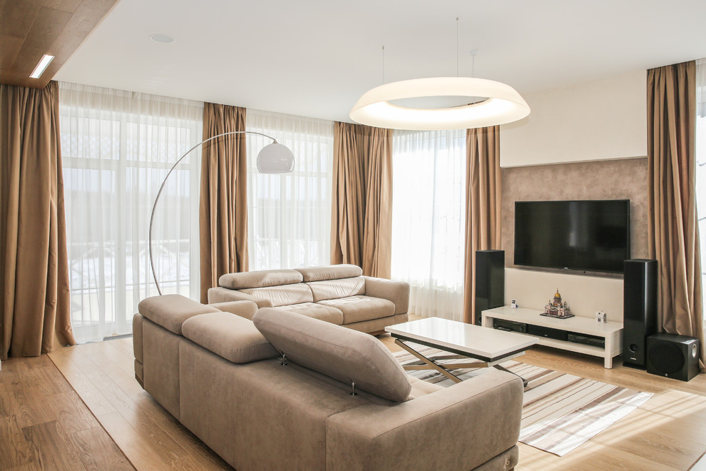 Modelo de salón para visitas abierto contemporáneo de tamaño medio con paredes beige, suelo de madera en tonos medios, televisor colgado en la pared y suelo marrón