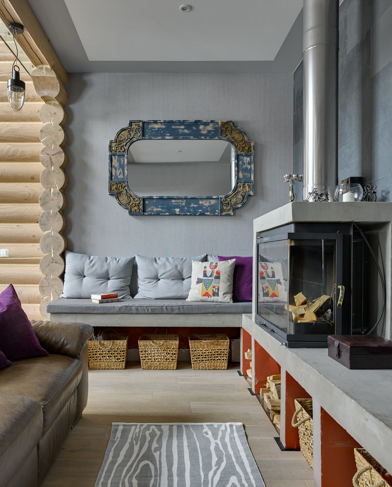 Diseño de salón campestre con paredes grises, suelo de madera clara, todas las chimeneas, marco de chimenea de hormigón y suelo beige