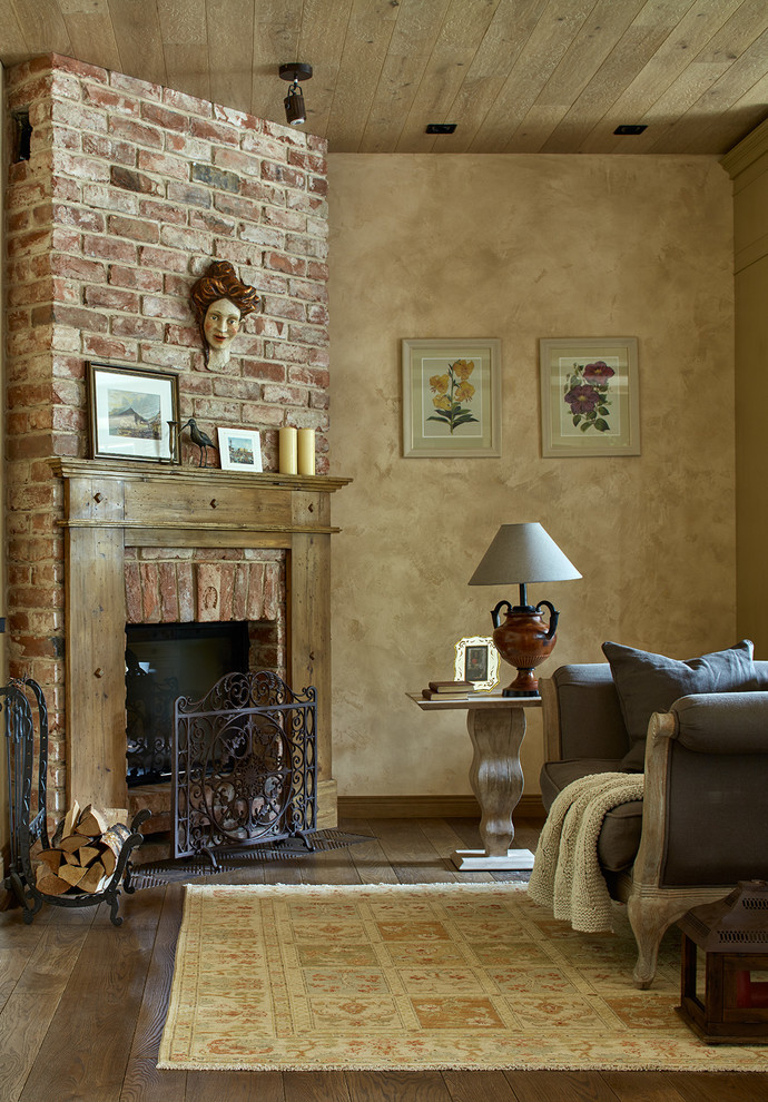 Réalisation d'un salon méditerranéen avec un mur beige, un sol en bois brun, une cheminée d'angle, un manteau de cheminée en brique et éclairage.