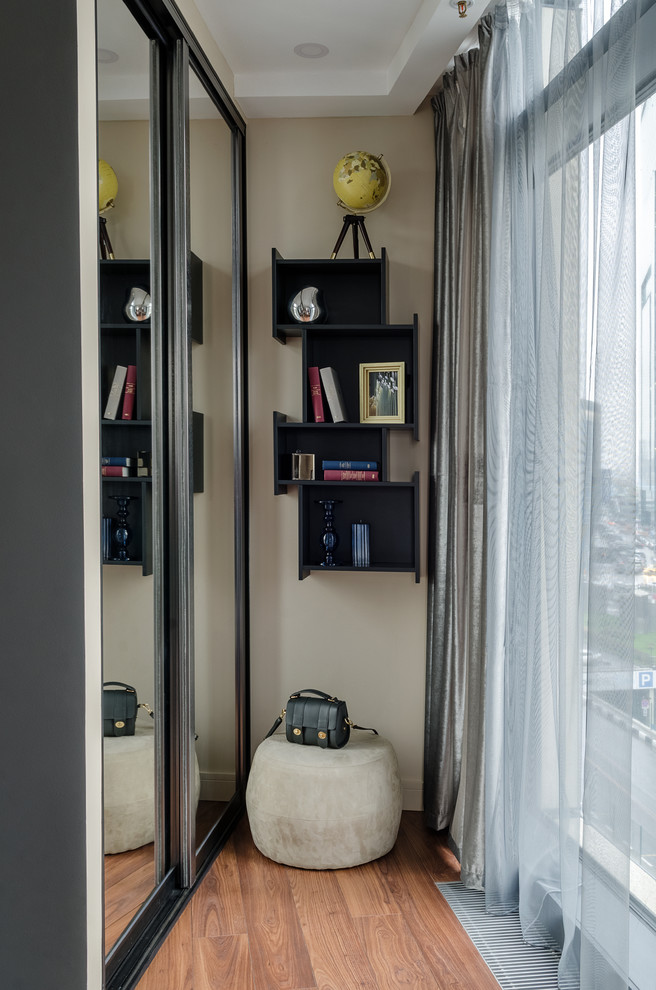 На фото: маленькая открытая, объединенная гостиная комната в современном стиле с с книжными шкафами и полками и бежевыми стенами для на участке и в саду