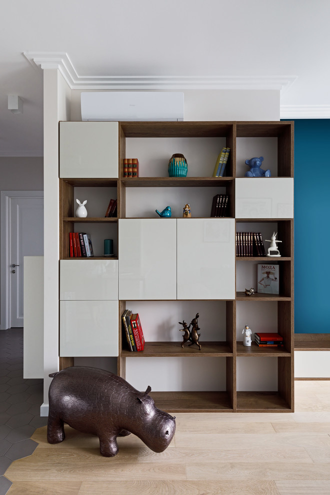 На фото: маленькая открытая, объединенная гостиная комната в современном стиле с с книжными шкафами и полками, синими стенами, светлым паркетным полом, телевизором на стене и бежевым полом для на участке и в саду