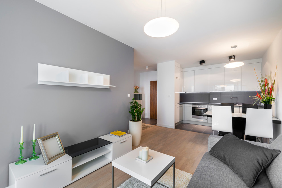 Стильный дизайн: открытая, объединенная гостиная комната среднего размера в скандинавском стиле с серыми стенами, паркетным полом среднего тона и отдельно стоящим телевизором без камина - последний тренд