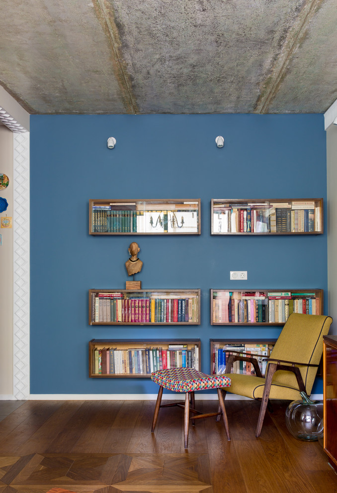 Réalisation d'un salon bohème avec une bibliothèque ou un coin lecture, un mur bleu, parquet foncé et un sol marron.