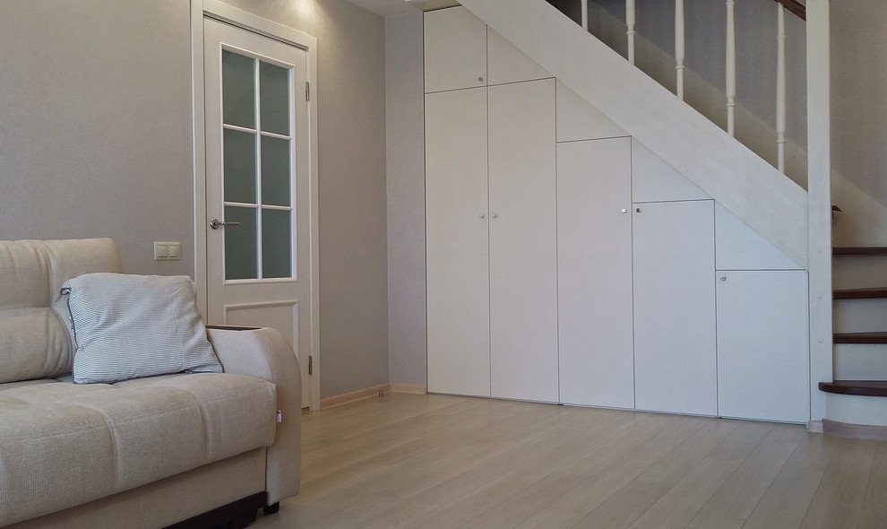 Пример оригинального дизайна: парадная, изолированная гостиная комната среднего размера в современном стиле с серыми стенами, полом из ламината, телевизором на стене и бежевым полом без камина