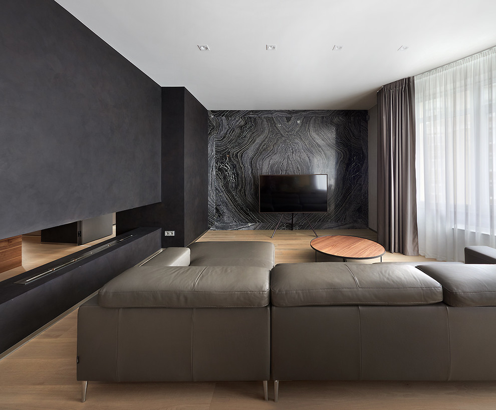 ロサンゼルスにあるラグジュアリーな広いコンテンポラリースタイルのおしゃれなリビング (黒い壁、淡色無垢フローリング、横長型暖炉、据え置き型テレビ、ベージュの床) の写真
