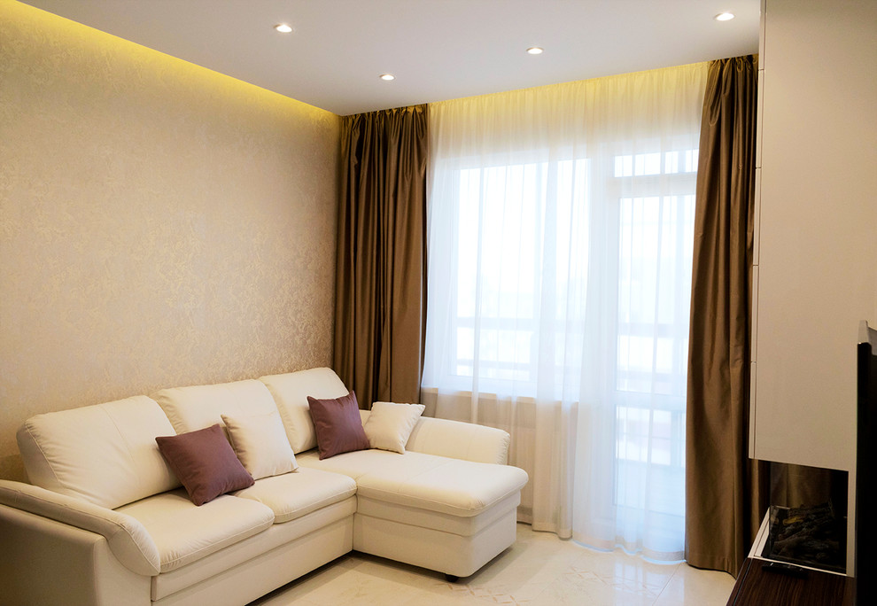 На фото: изолированная гостиная комната среднего размера в современном стиле с бежевыми стенами, полом из керамической плитки, телевизором на стене, бежевым полом и тюлем на окнах