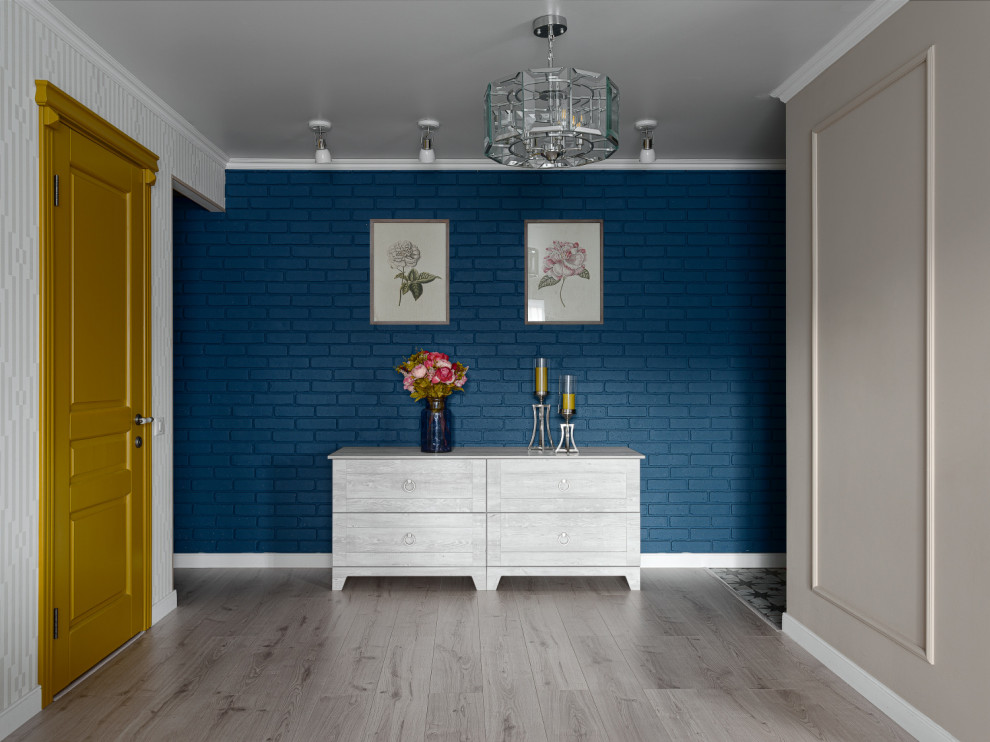 На фото: открытая гостиная комната в стиле неоклассика (современная классика) с синими стенами, полом из ламината, бежевым полом и кирпичными стенами