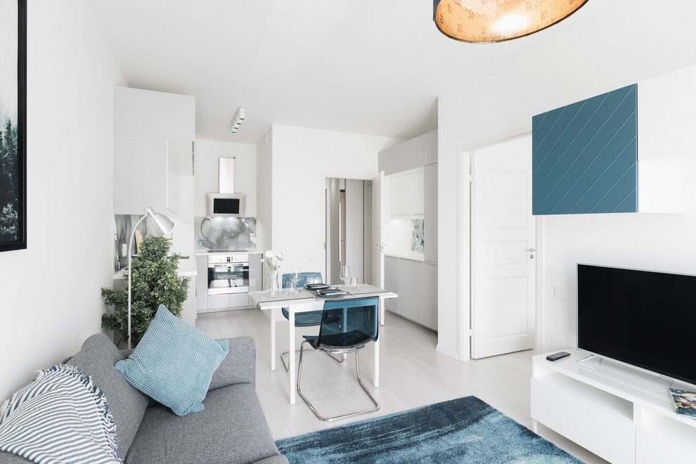 Стильный дизайн: открытая гостиная комната в скандинавском стиле с белыми стенами, полом из ламината и серым полом - последний тренд