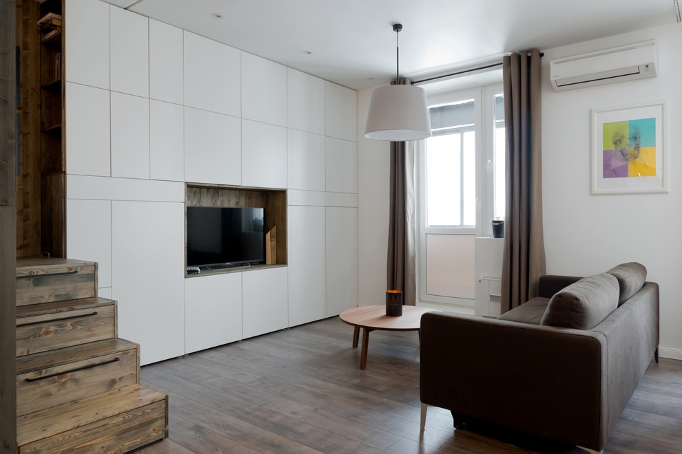 Пример оригинального дизайна: маленькая гостиная комната в современном стиле с белыми стенами, полом из ламината и отдельно стоящим телевизором для на участке и в саду
