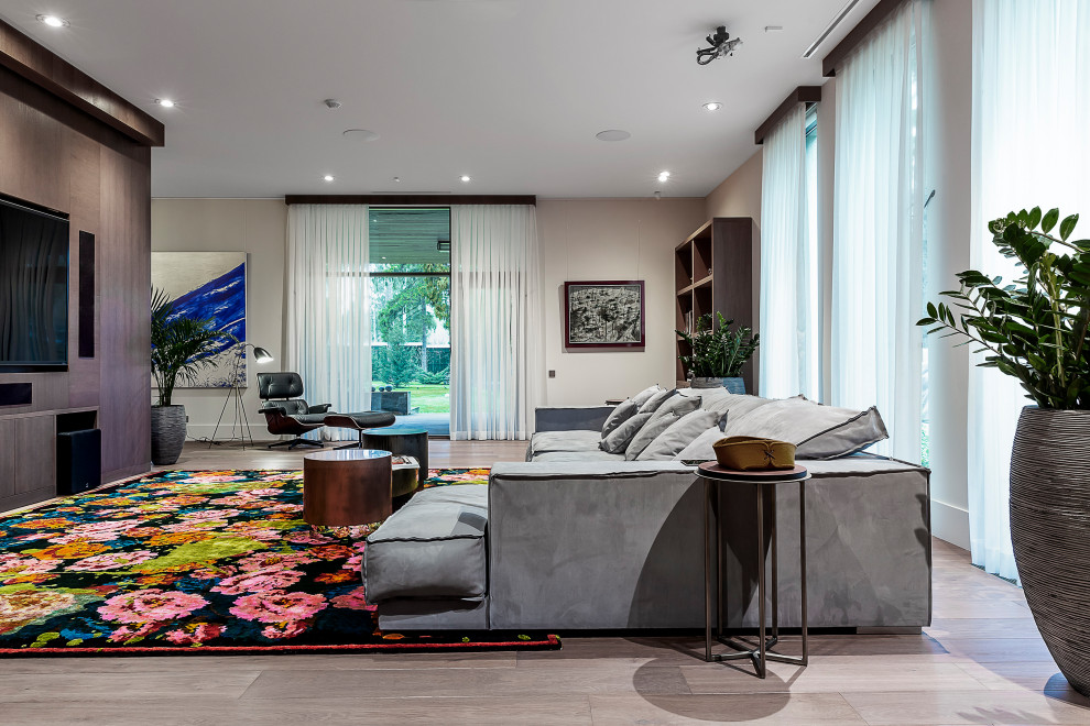 Aménagement d'un grand salon contemporain ouvert avec un mur gris, un téléviseur encastré et un sol beige.