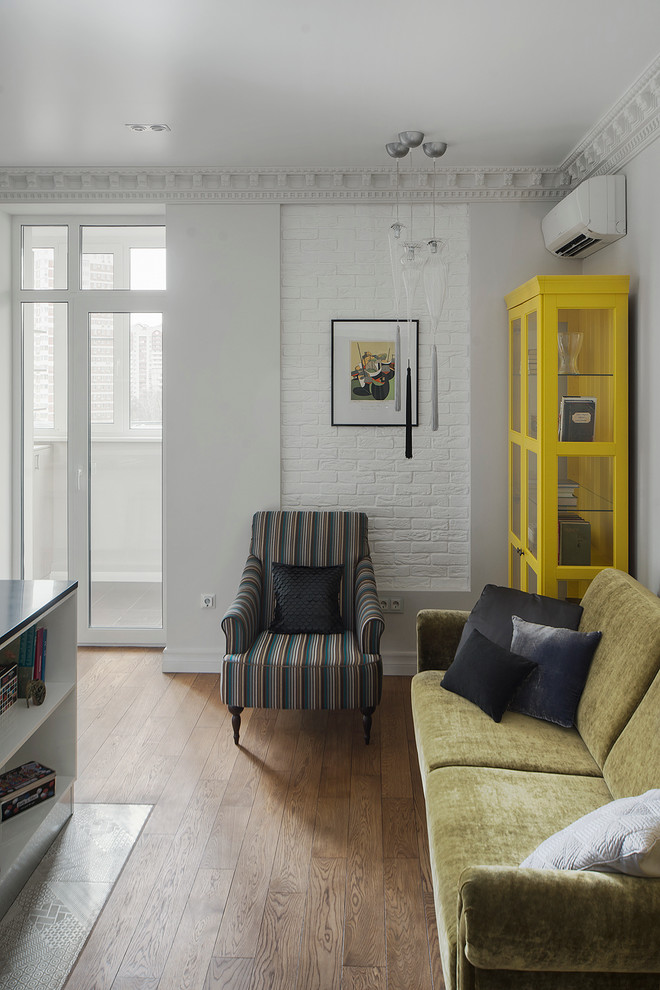 Стильный дизайн: гостиная комната в стиле фьюжн с белыми стенами, паркетным полом среднего тона и горчичным диваном - последний тренд