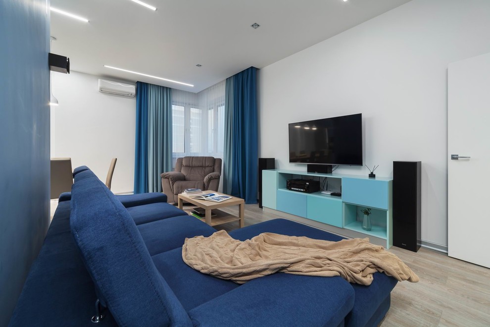 Ejemplo de salón abierto contemporáneo de tamaño medio con paredes azules, suelo laminado, televisor colgado en la pared y suelo marrón