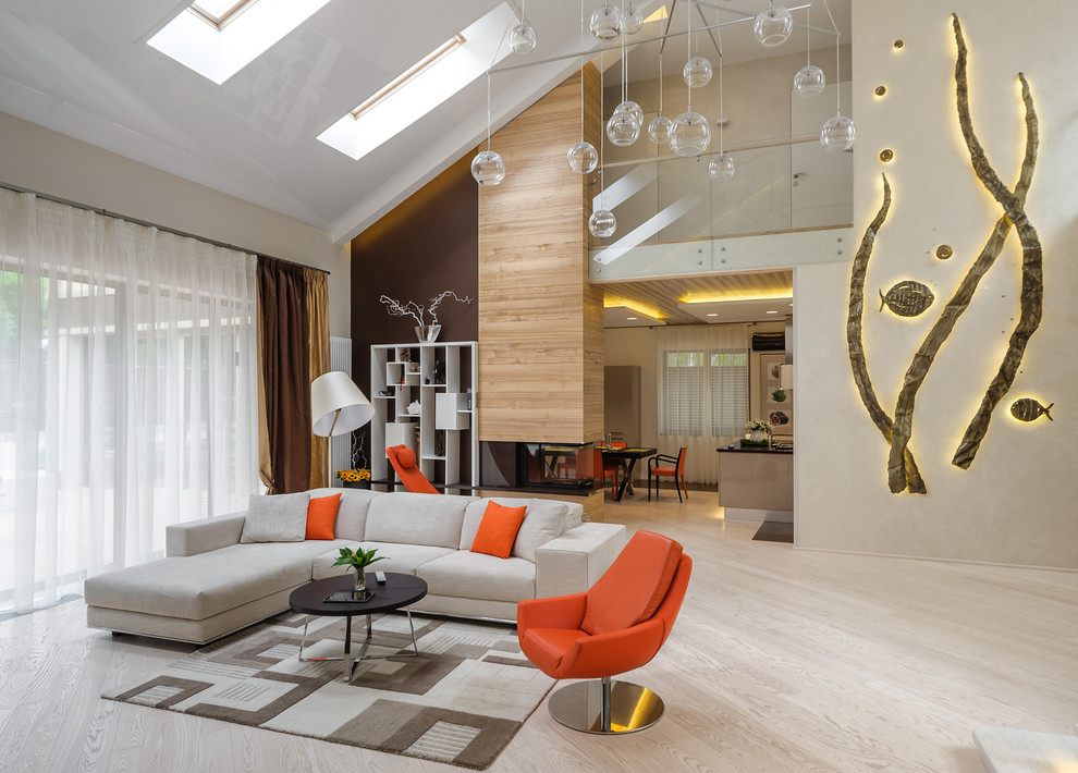 Источник вдохновения для домашнего уюта: огромная открытая гостиная комната в современном стиле с бежевыми стенами, светлым паркетным полом, двусторонним камином и фасадом камина из дерева