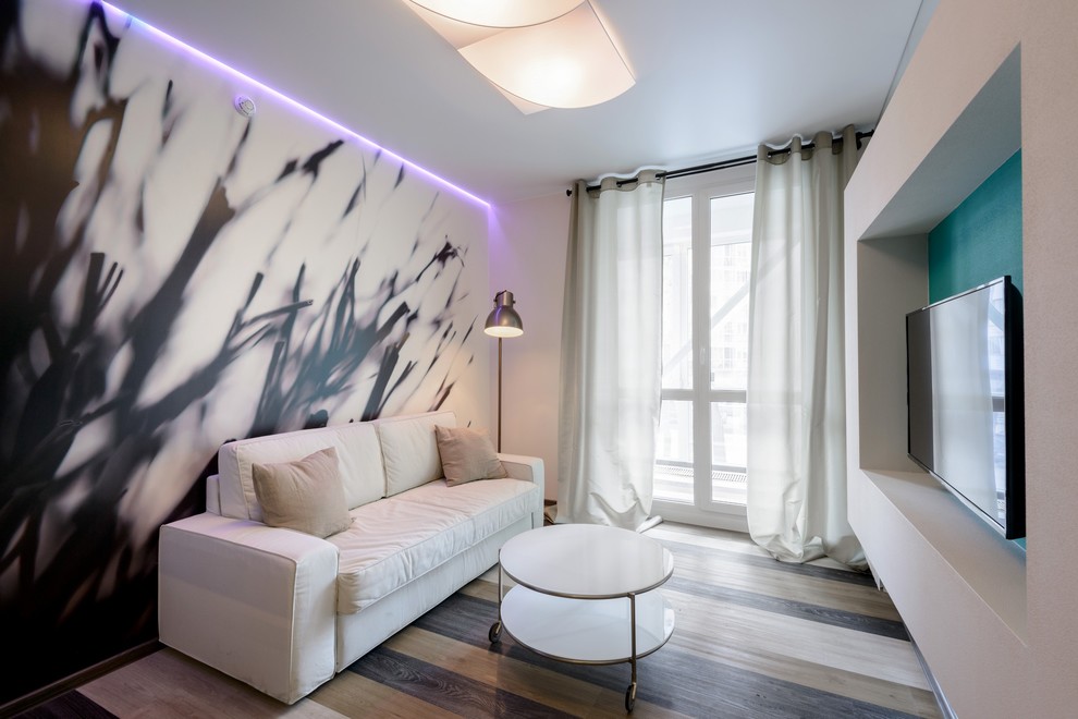 На фото: маленькая открытая, объединенная гостиная комната в современном стиле с белыми стенами, полом из винила, телевизором на стене и бежевым полом для на участке и в саду