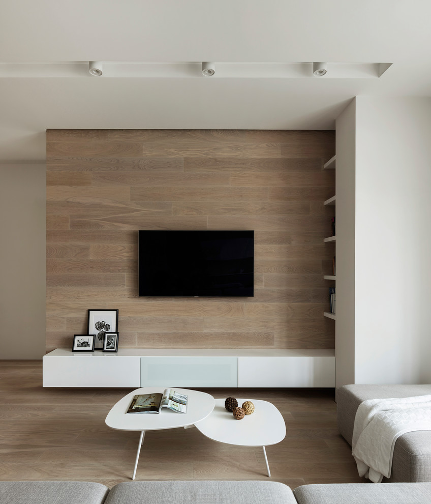 Стильный дизайн: парадная, открытая гостиная комната в стиле модернизм с серыми стенами, светлым паркетным полом и телевизором на стене - последний тренд