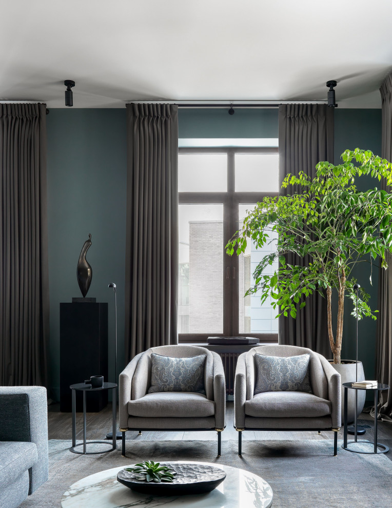 Пример оригинального дизайна: большая гостиная комната в современном стиле с зелеными стенами, паркетным полом среднего тона, телевизором на стене и коричневым полом